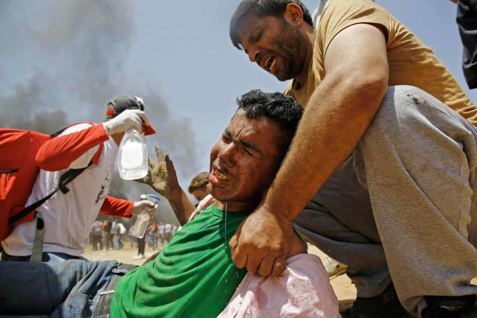 Un joven palestino es asistido durante los enfrentamientos con las fuerzas de seguridad israelíes en la frontera entre Gaza e Israel, el 14 de mayo de 2018. MOHAMMED ABED AFP