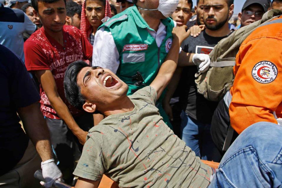 Personal de emergencias trasladan a un herido durante los enfrentamientos con las fuerzas de seguridad israelíes en la frontera entre Gaza e Israel, el 14 de mayo de 2018. MOHAMMED ABED AFP