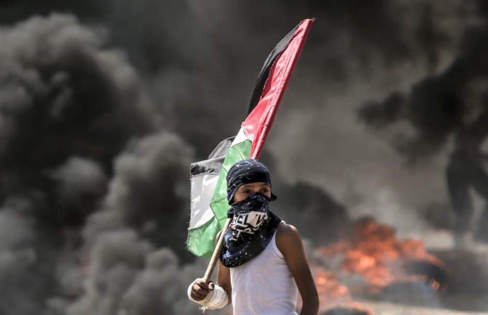 Un niño sujeta la bandera de Palestina durante los enfrentamientos en la franja de Gaza, el 14 de mayo de 2018. MAHMUD HAMS AFP