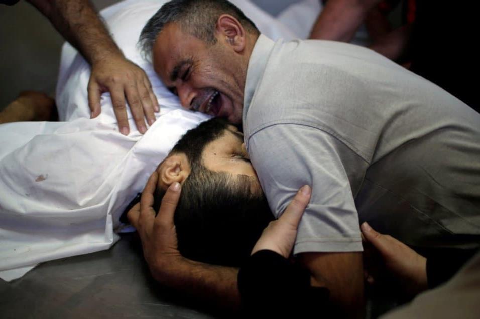 Shaher al-Madhoon, que murió durante la protesta en la frontera entre Israel y Gaza, y su hermano que reacciona por encima de su cuerpo en la morgue de un hospital en el norte de la franja de Gaza el 14 de mayo de 2018. MOHAMMED SALEM REUTERS