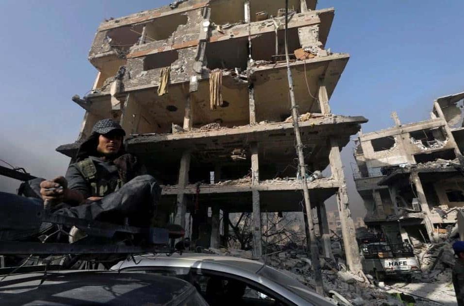 Un soldado del Ejército sirio se fuma un cigarro frente a un edificio en escombros en al-Hajar al-Aswad, el 21 de mayo de 2018. OMAR SANADIKI REUTERS