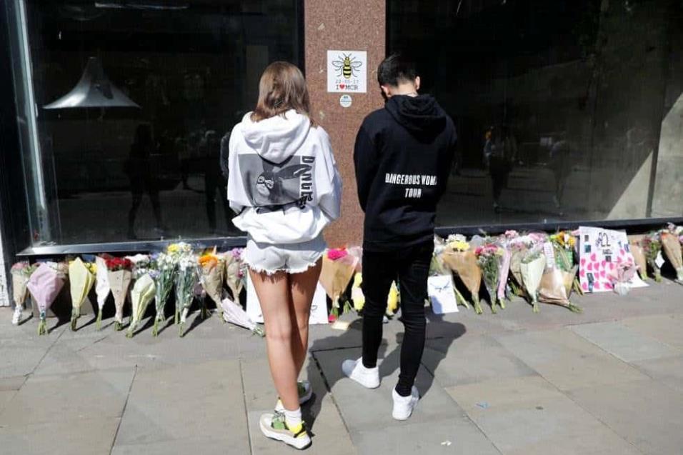 Dos jóvenes con sudaderas de Ariana Grande dejan flores en la plaza de Santa Ana en Manchester, en el primer aniversario del atentado en el Manchester Arena. DARREN STAPLES REUTERS